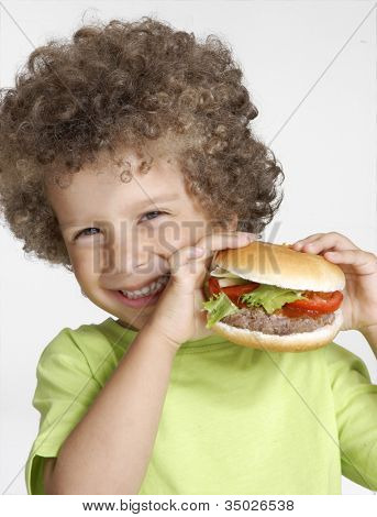 작은 아이 큰 햄버거를 들고 햄버거를 먹고.