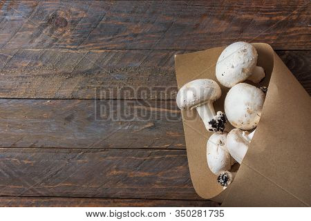 Bunch Of Freshly Picked White Button Mushrooms In Brown Paper Bag On Rustic Wood Table. Plastic Free