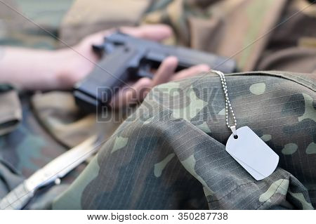 Army Token Lies On Camouflage Uniform Of Dead Soldier And Hand With Pistol