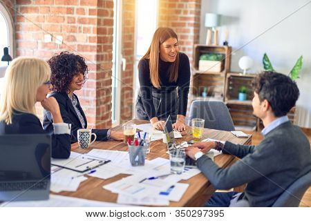 Group of business workers smiling happy and confident. Working together with smile on face. Young beautiful woman standing explaining documents at the office