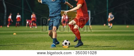 Two Men Kicking Soccer Ball. Junior Teenage Soccer Team On Training Game.  Athletes Running With Bal