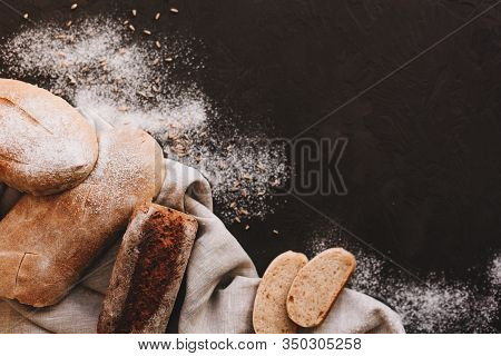 Various Crispy Bread And Buns On The Stone Table, Loaf Of Fresh Baked Artisan Sliced Rye Bread Over 