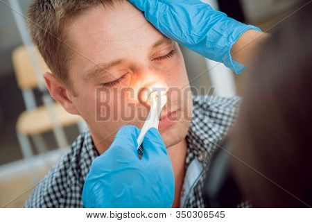 Otolaryngologist Examines Mans Nose With Nasal Dilator. Medical Equipment