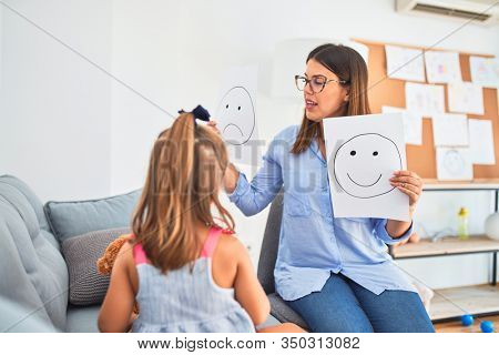 Young therapist woman speaking and treating child, counselor and behaviour correction at pedagogue payroom showing happy and sad faces
