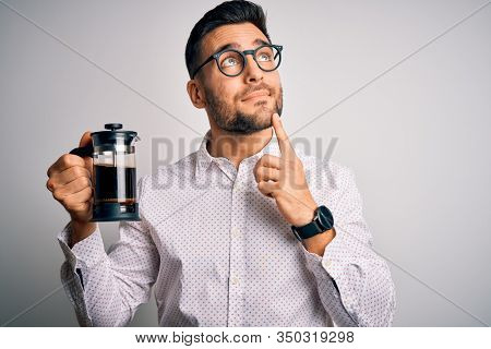 Young handsome man making coffee using french press coffeemaker over isolated background serious face thinking about question, very confused idea