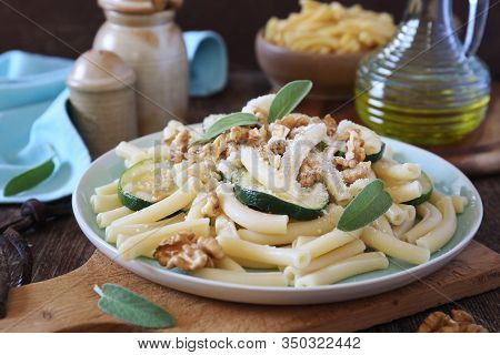 Italian Penne Pasta With Roasted Zucchini, Grated Parmesan Cheese And Walnuts On Wooden Background, 