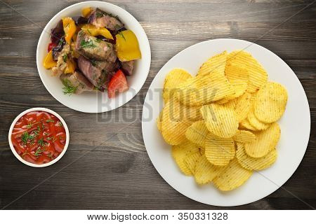 Potato Chips On A White Plate With Vegetarion Salad. Chips On A Black Wooden Background Top View.