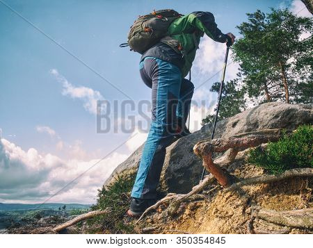 Man Hiker Climb Use Trekking Sticks. Walks Carefully On Slippery Sandstone Rocks.
