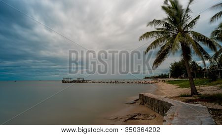Palm Tree And  Walkeway In Front Of Dilapidated Old Fishing Dock Collapsing Into The Sea In Pak Nam 