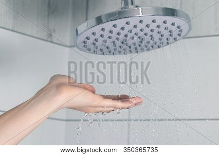 Female Hand Touching Water Pouring From A Rain Shower Head, Checking Water Temperature