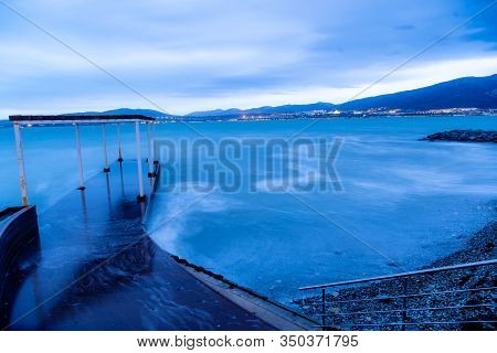 Gelendzhik Beach In The Evening In A Storm. The Waves At High Speed Turn Into A Blue Fog. Blue Tones