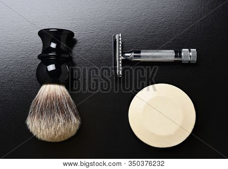 Flat Lay Shaving Still Life. A razor shaving brush and bar of soap on black.