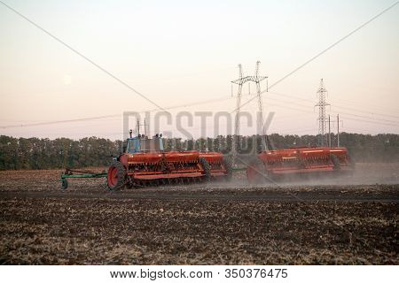 Agricultural Mechanical Seeders Of Grain Crops. Tactor With A Seeder Sows Grain In The Field. A Farm