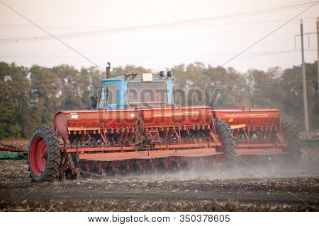 Agricultural Mechanical Seeders Of Grain Crops. Tactor With A Seeder Sows Grain In The Field. A Farm