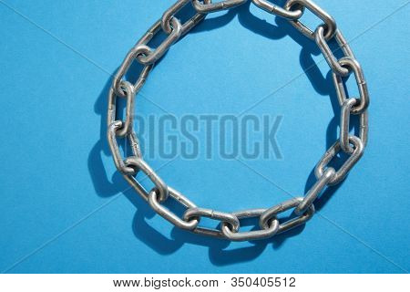 Taunt stainless steel chain on blue background - closeup