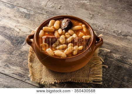 Typical Spanish Fabada Asturiana In Crockpot On Wooden Table