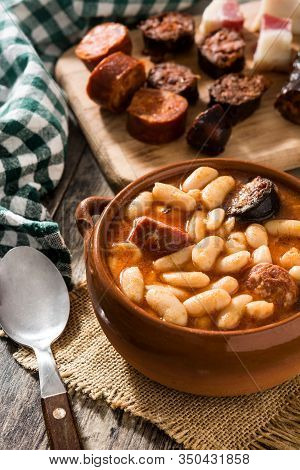 Typical Spanish Fabada Asturiana In Crockpot On Wooden Table