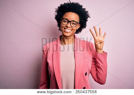 Young beautiful African American afro businesswoman with curly hair wearing pink jacket showing and pointing up with fingers number four while smiling confident and happy.