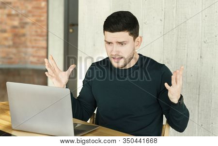 Computer Problem. Unhappy Man At Laptop Gesturing With Hands Having Issue At Work In Modern Office. 