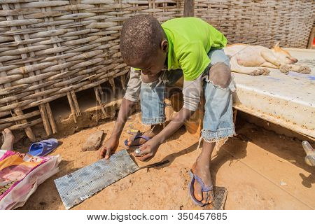 Bissau, Guinea-Bissau - January 5, 2020: portrait on an African Kid and his dog, in rural Guinea-Bissau