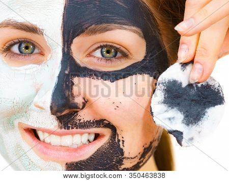 Woman With Clay Carbo Black Mask On One Half Face And White Mud On Second Half. Girl Removing Cosmet