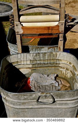 A Wet Towel Has Been Fed Through The Rollers Of A Vintage Wringer Washing Machine And Is Collected I
