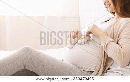 Expecting For Firstborn. Pregnant Woman Playing With Small Booties And Her Belly, Panorama, Empty Sp