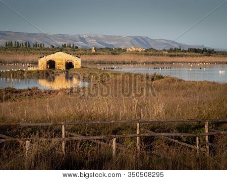 A Ruined Building Reflecting Into The Water With Birds On Top Of It