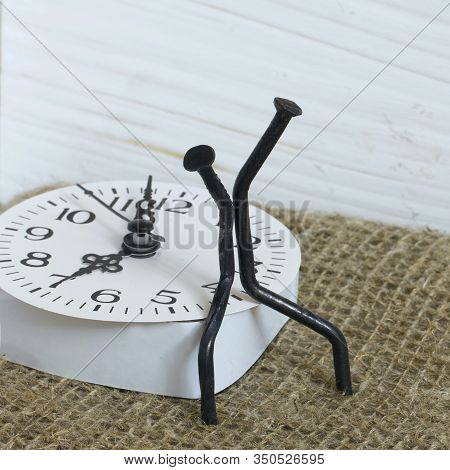 Figurines Of Man Made From Carpentry Nails. Sit On The Watch Dial Back To Back. Symbol Of The Inexor