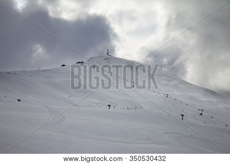 Snowy Ski Slope, Chair-lifts In High Mountains And Cloudy Storm Sky At Winter Before Blizzard. Ski A