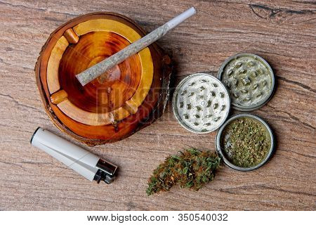 Close Up Of Cannabis - Marijuana Bud And Accessories - Grinder, Wooden Ashtray, Lighter And Rolled J