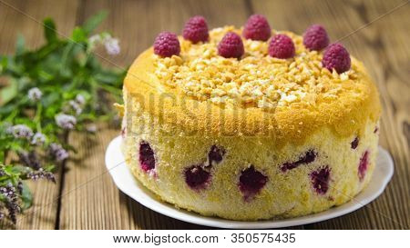 Beautiful Pastry, Cake, With Raspberries On Old Boards. The Girl Decorates The Cake With Mint.