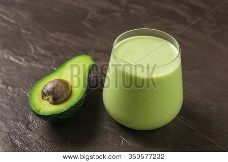 A Glass Of Avocado And Spinach Smoothies And Half An Avocado On A Stone Background. Fitness Product.