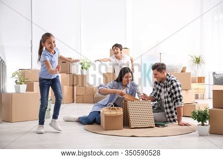 Happy Family Unpacking Moving Boxes At Their New Home