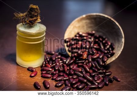 Close Up Of Raw Kidney Beans On Brown Colored Surface In A Clay Bowl And Its Oil In A Small Transpar