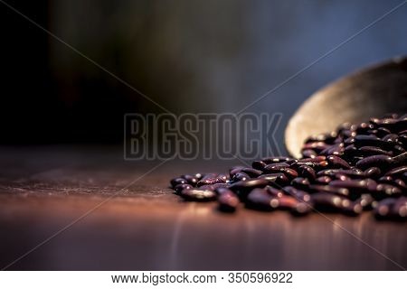Close Up Of Raw Kidney Beans On Brown Colored Surface In A Clay Bowl With A Spotlight On It. Horizon