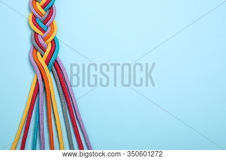 Top View Of Braided Colorful Ropes On Light Blue Background, Space For Text. Unity Concept