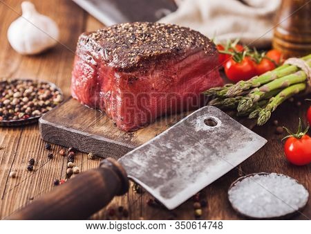 Slice Of Raw Beef Topside Joint With Salt And Pepper On Wooden Chopping Board With Meat Hatchet, Gar