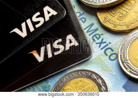 Lutsk, Ukraine - 02-08-2020: Visa Logo On Two Credit Cards Laying On The Peso Banknote And Coins Wit