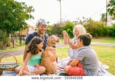 Happy Family With Their Dog In A Good Summer Day. The Family Playing With Dog. Happy Family Doing Pi