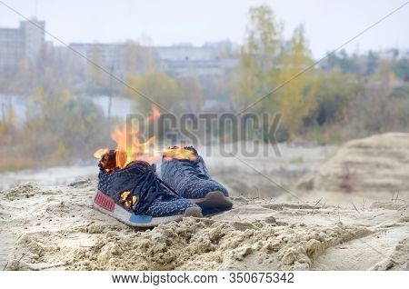 Burning Sports Sneakers Or Gym Shoes On Fire Stand On Sandy Beach Coast. Athlete Burned Out. Physica