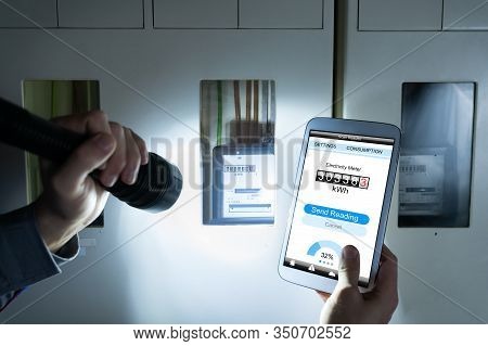 Man's Hand Holding Mobile Phone Showing Electric Meter Reading