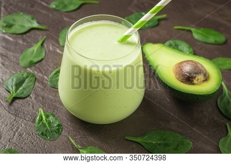 Half An Avocado And A Glass Of Smoothies On A Stone Background With Spinach Leaves. Fitness Product.