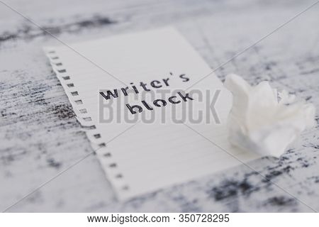 Piece Of Paper On Wooden Desk With Writer's Block Text With Scrunched Paper Ball Next To It