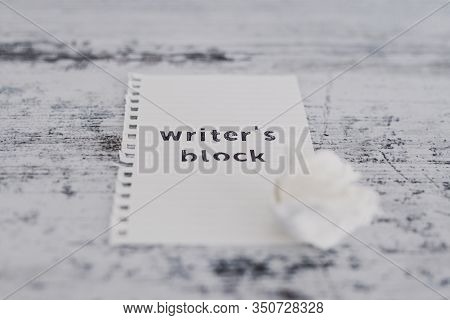Piece Of Paper On Wooden Desk With Writer's Block Text With Scrunched Paper Ball Next To It