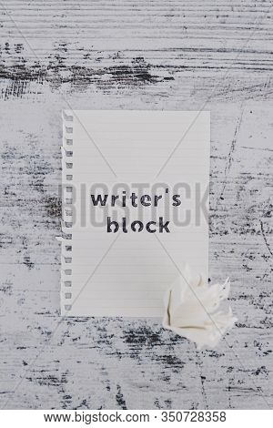 Piece Of Paper On Wooden Desk With Writer's Block Text With Scrunched Paper Ball Next To It