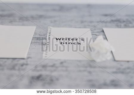 Piece Of Paper On Wooden Desk With Writer's Block Text Surrounded By Blank Notepads And With With Sc