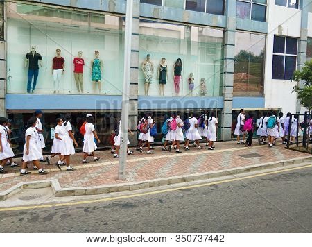 A Crowd Of Schoolchildren In White Clothes Are Walking In A Column Along The Street. Colombo / Sri L