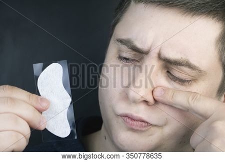 A Man Puts On And Removes A Strip For The Nose From Black Dots. Coal Cleaning Strips From Blackheads