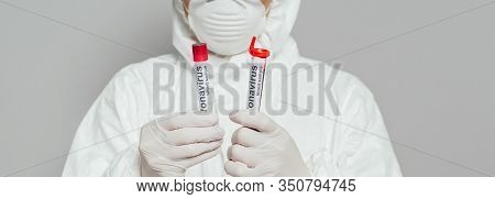Cropped View Of Epidemiologist In Hazmat Suit And Respirator Mask Holding Test Tubes With Blood Samp